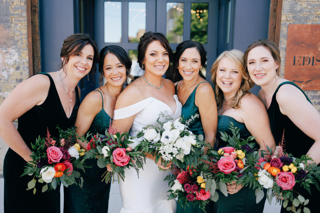 Bride and bridesmaids with emerald dresses and bright flower bouquets 