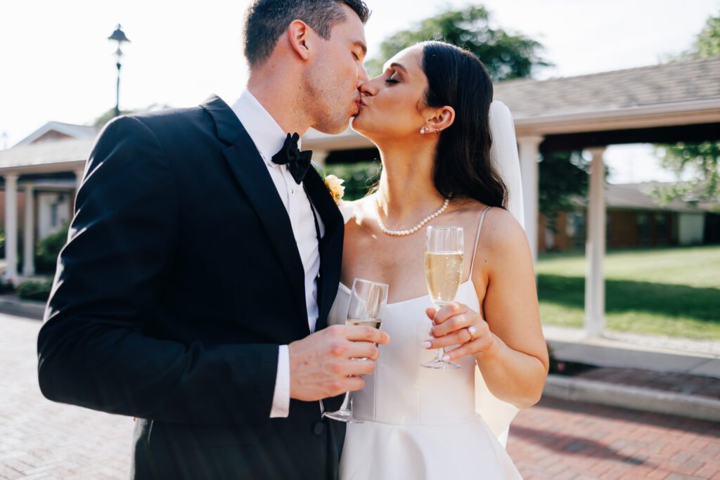 bride and groom kiss with champagne
