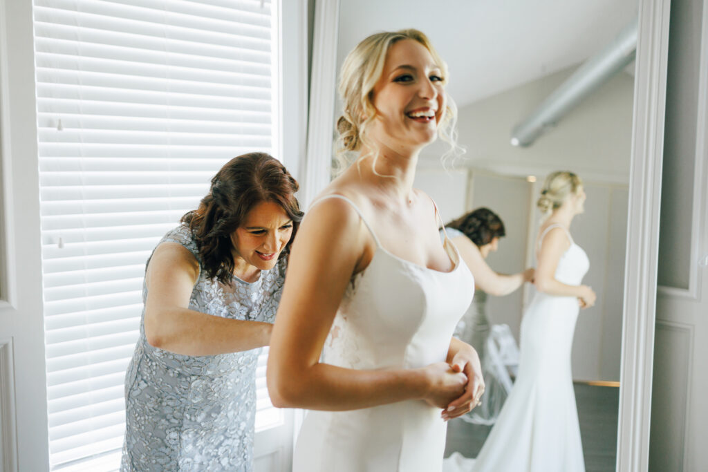 brides mom zips dress as she puts on her gown
