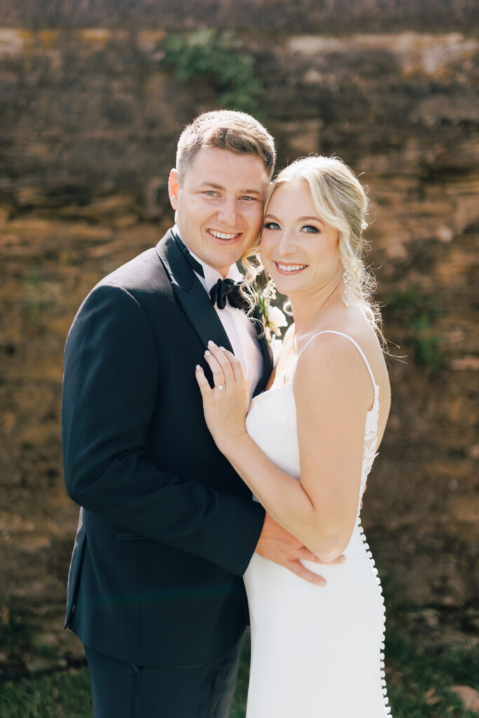 bride and groom backlit posing toward the camera smiling at Swan Lake Wedding venue