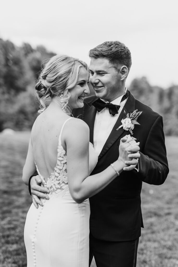 black and white photo of bride and groom dancing in open field at Swan Lake Wedding venue