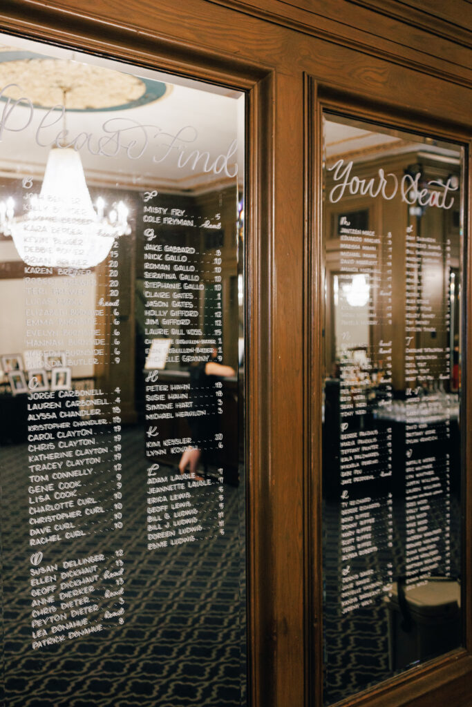 wedding seating chart hand calligraphed onto glass mirror at the athletic club wedding venue