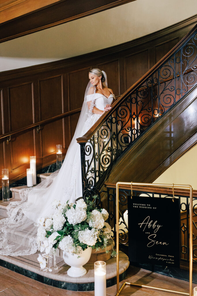 bride on staircase full of florals and candlight