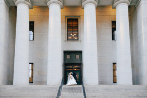 bride and groom kiss infront of marble pillars and staircase