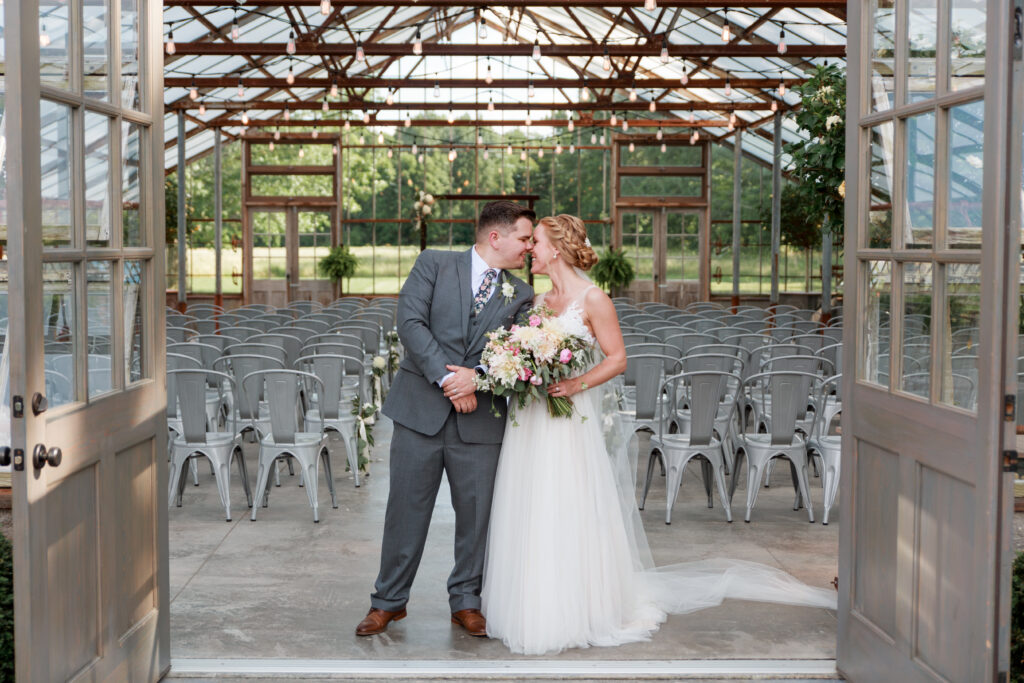 couple kissing in front of glass greenhouse wedding venues in Columbus oh