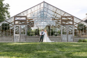 Glass Greenhouse event venue with bride and groom standing outside at Jorgensen Farms 