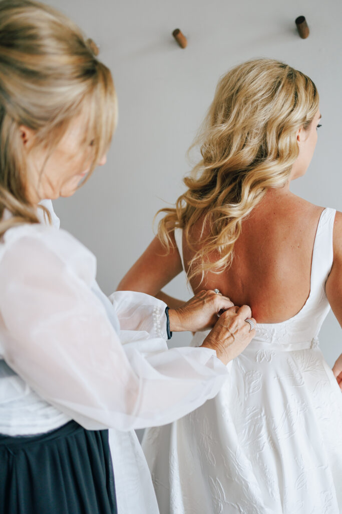mother of bride zips up brides gown