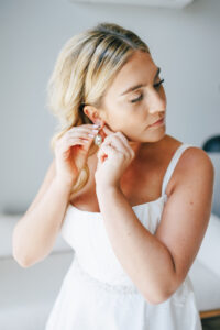 bride stands near window and puts on diamond earring at wedding venues in Columbus oh