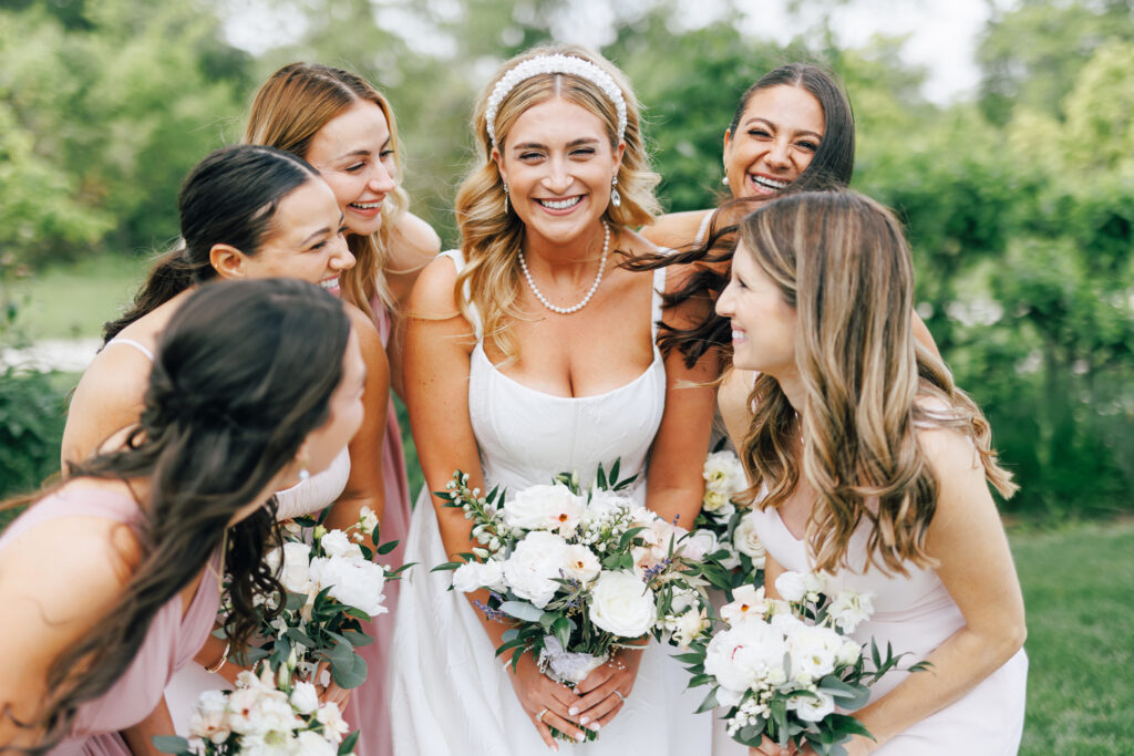 bride surrounded by bridesmaids in grassy field at wedding venues in Columbus oh