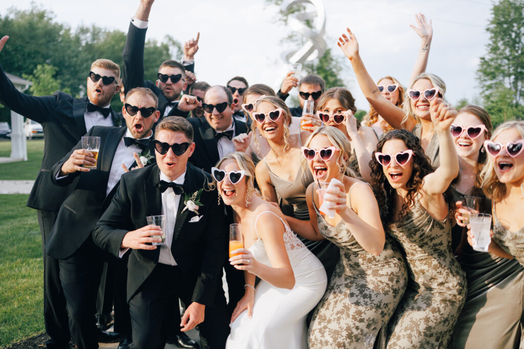 bridal party wearing heart shaped sunglasses with cocktails in hand