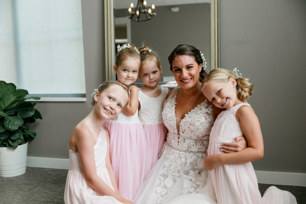 bride cuddles with four flower girls wearing pink gowns at The Estate New Albany