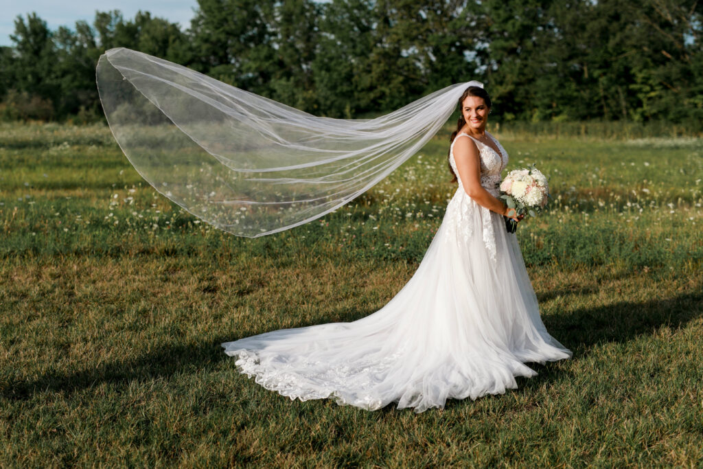 bride stands in field of wild flowers with view blowing in the breeze at The Estate New Albany