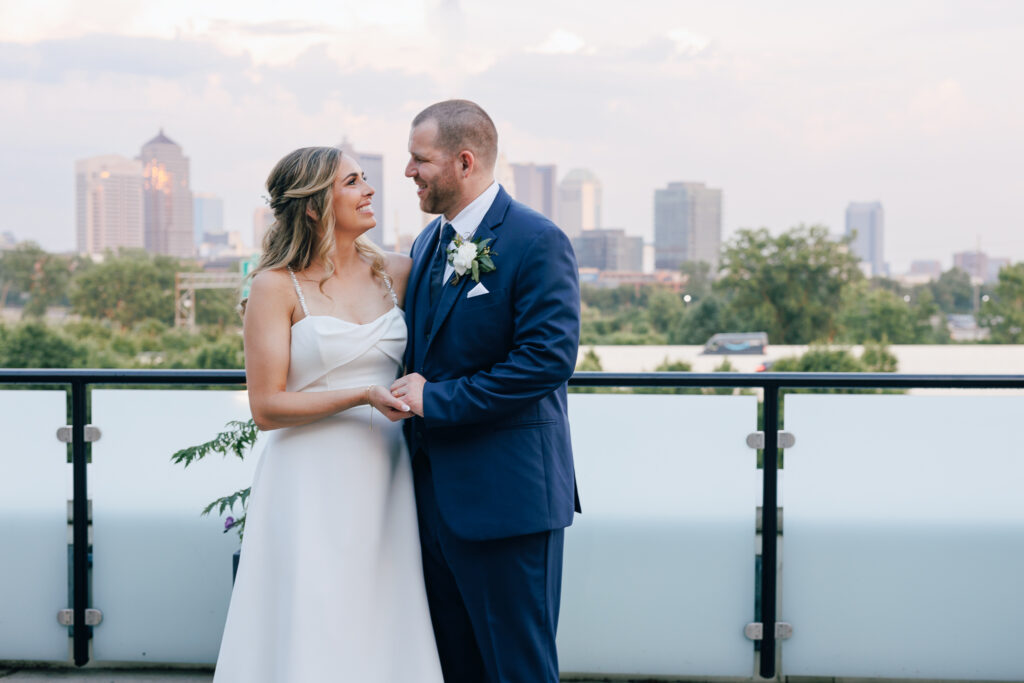 bride and groom on rooftop of The fives wedding venue in Columbus Ohio with a pink Columbus skyline behind them. 