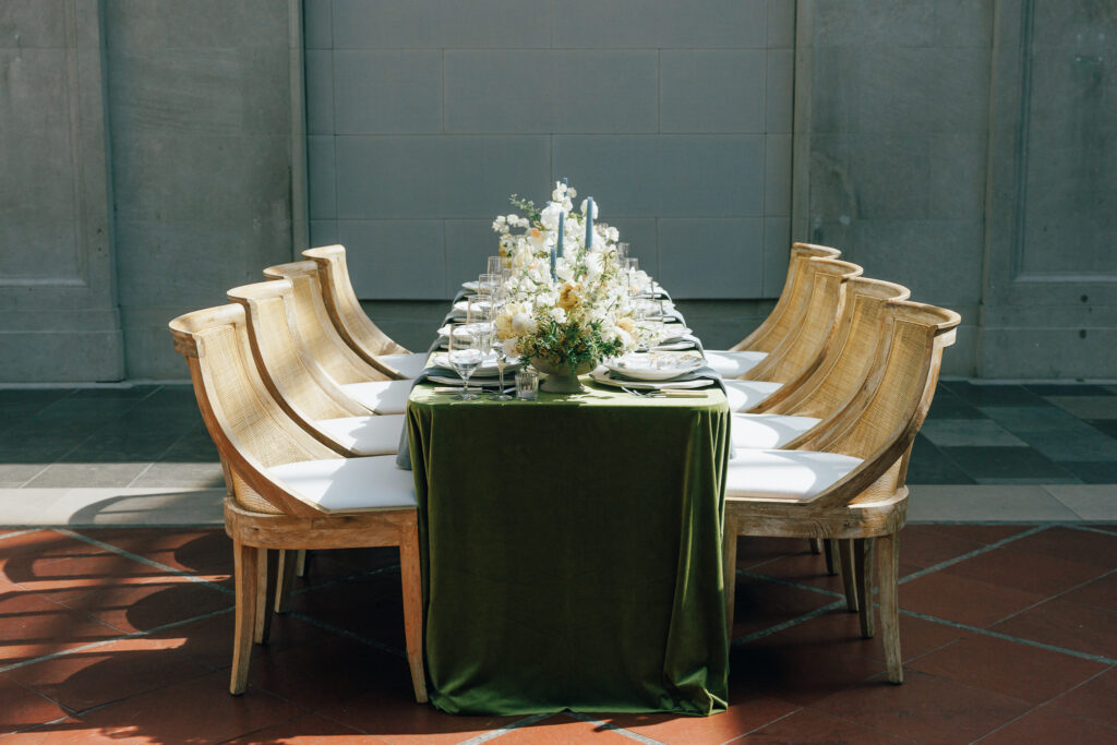 styled wedding table with green velvet table linens and floral centerpieces. Set against marble wall backdrop at Columbus Museum of Art wedding venue