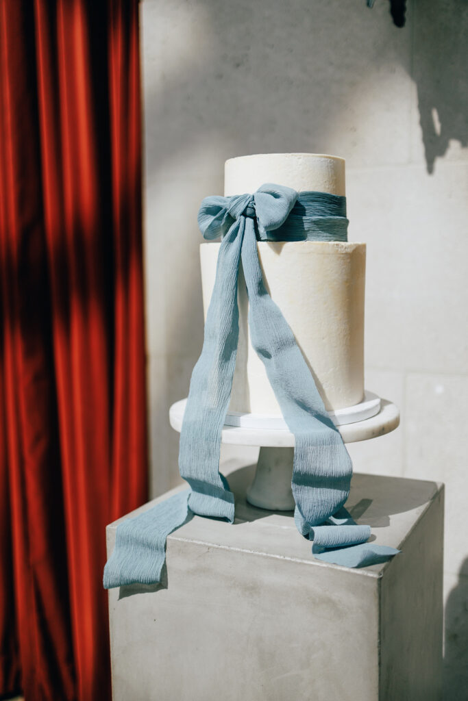 Cake on cement square stand with blue bow cascading down at the Columbus Art Museum wedding venue