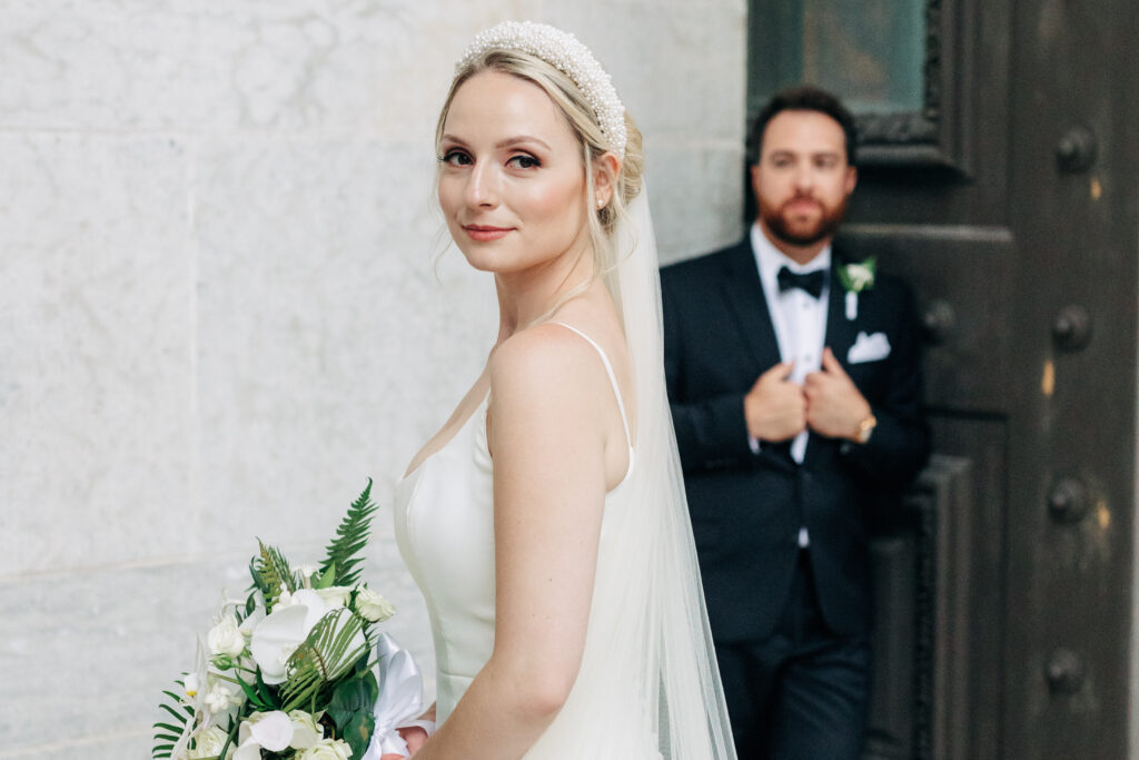 bride looks into the camera as groom stands behind her at The Ohio Statehouse