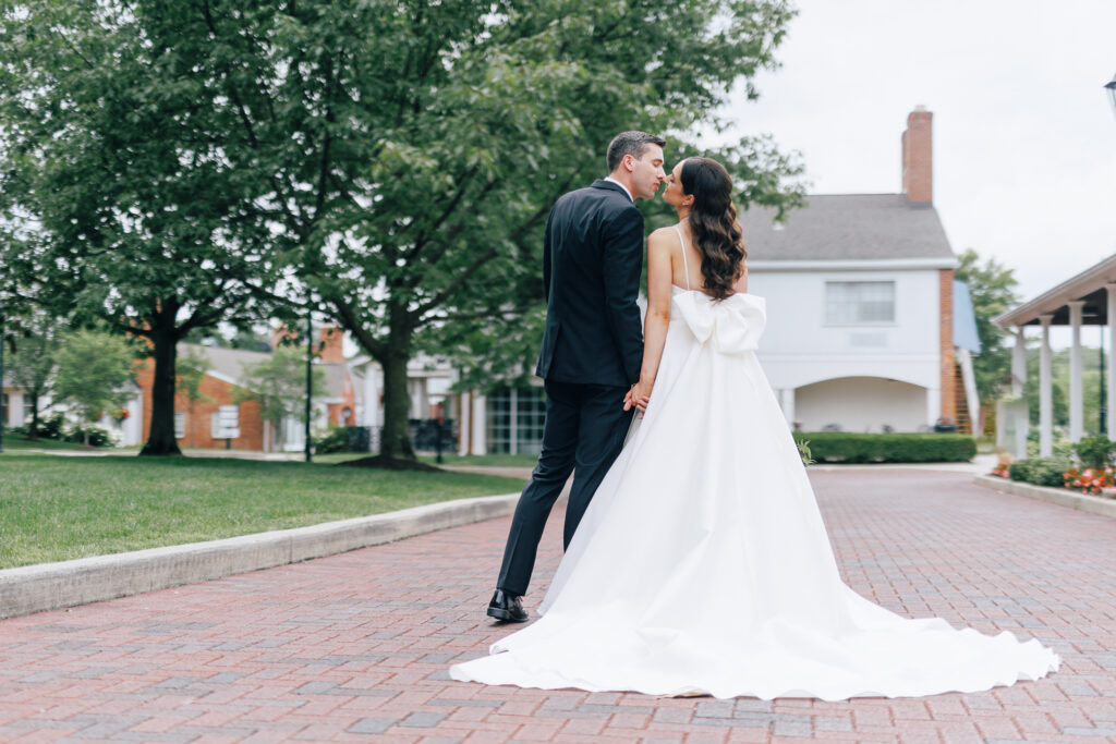 bride and groom kiss on brick road infront of charming white building in columbus ohio