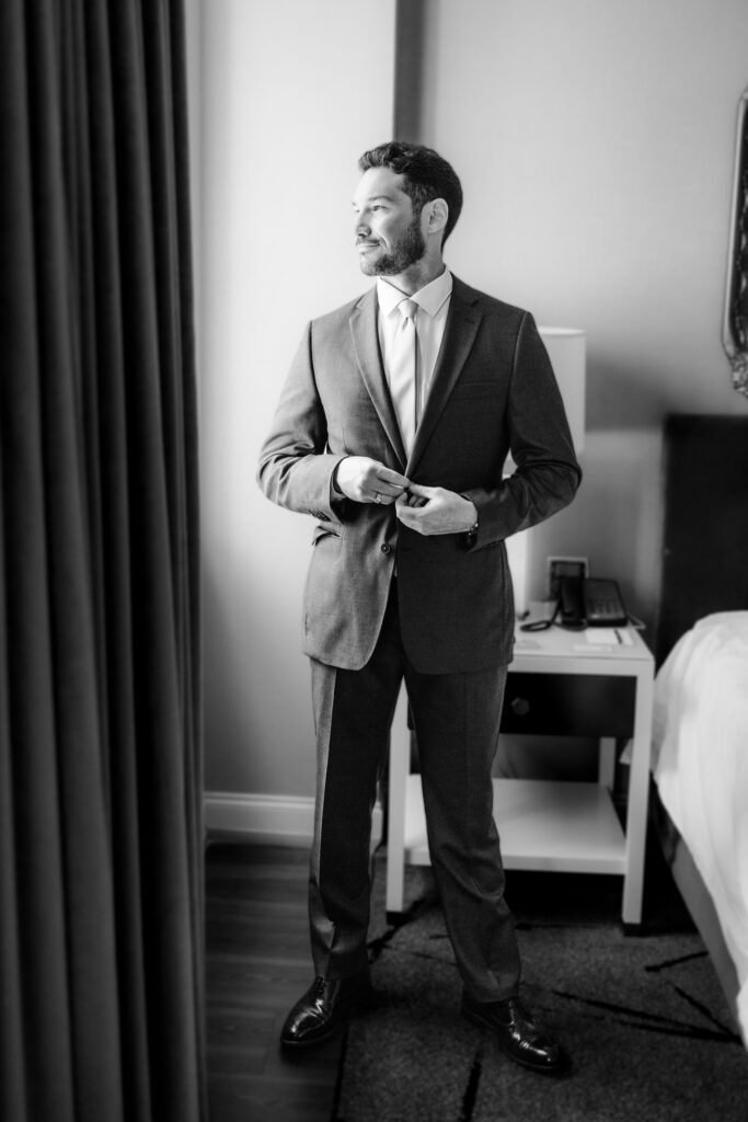 Groom buttoning suit jacket at the leveque hotel