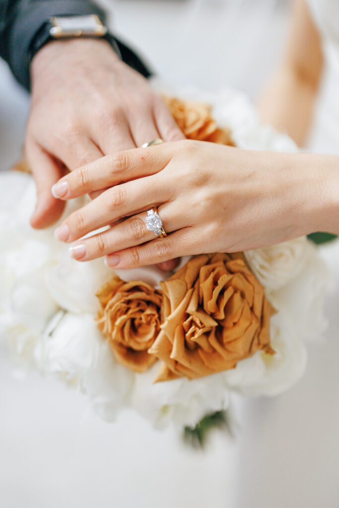 bride and groom hands crossed over bridal bouquet with wedding rings at the leveque hotel