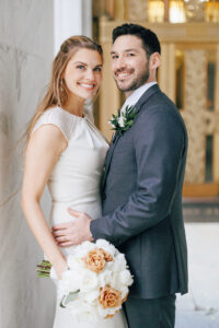 bride and groom pose infront of gold doors at the leveque hotel