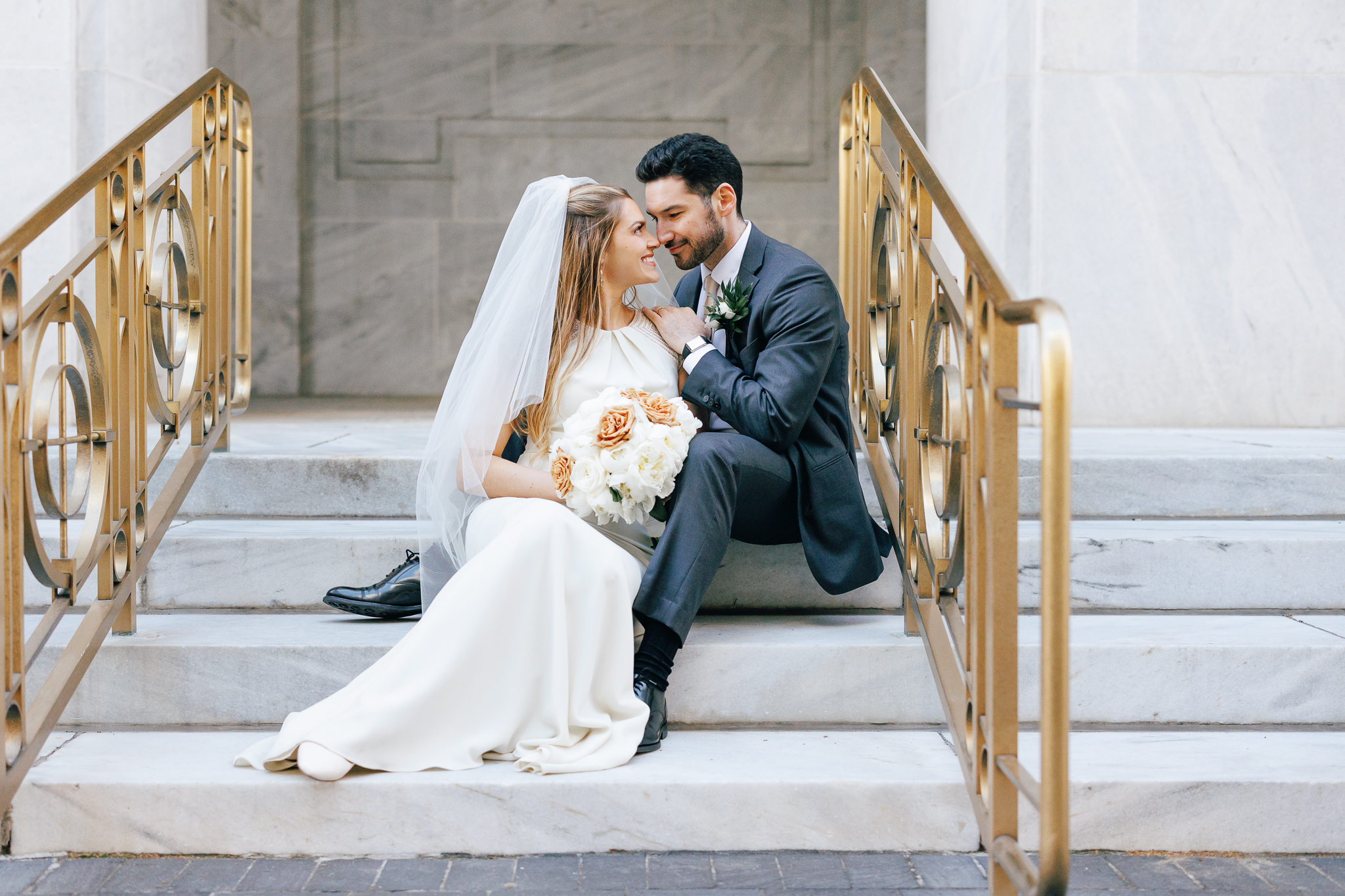bride and groom on steps with gold banisters at the leveque hotel